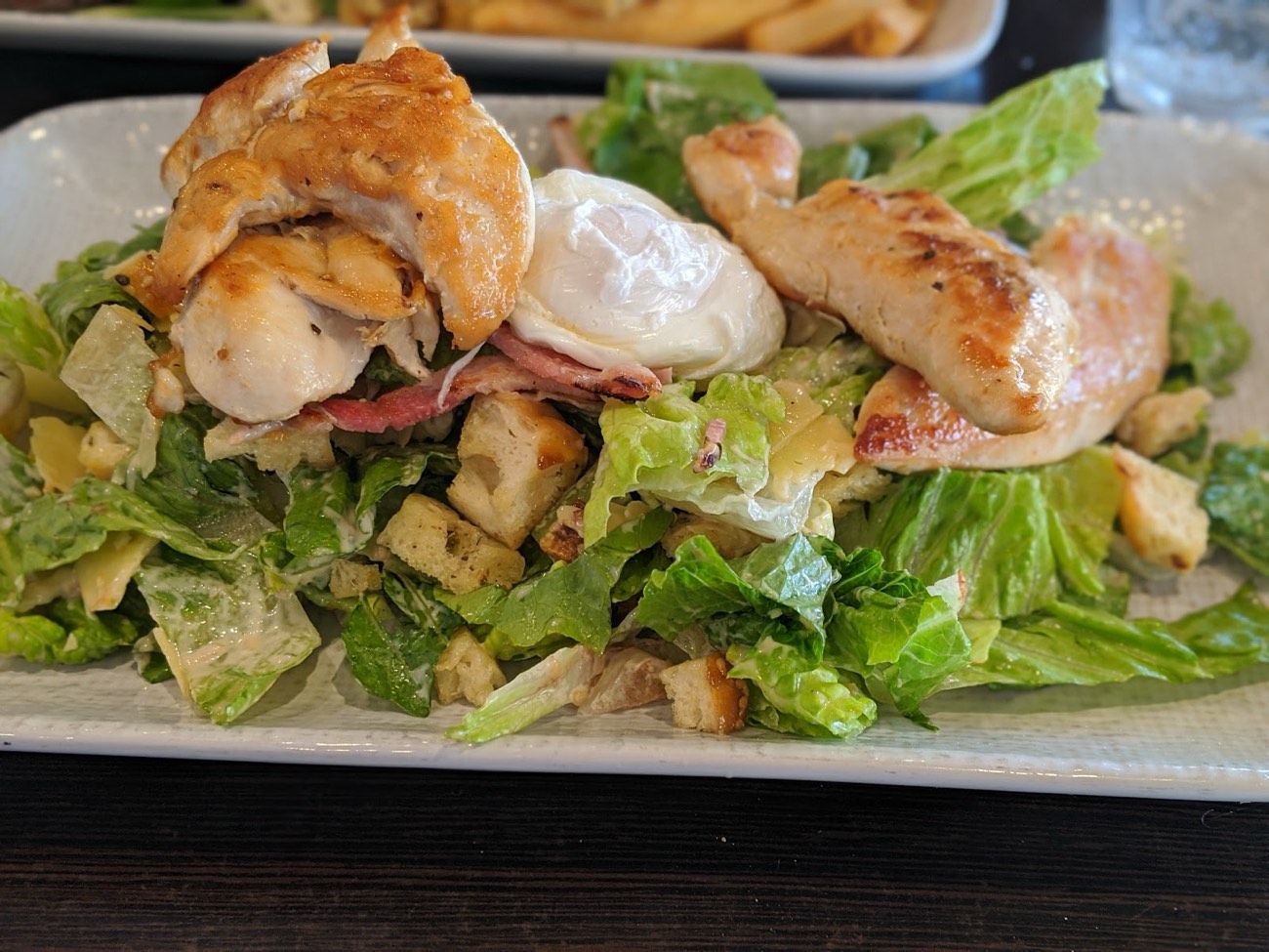 Grilled chicken caesar salad with a poached egg